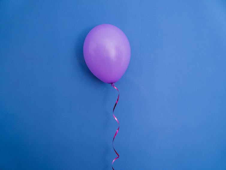 Um balão roxo estourado em um fundo azul.